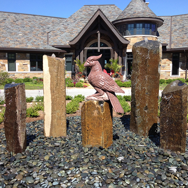 Large Bubbling Basalt Column Fountains with Carved Cardinal Statue made of red granite