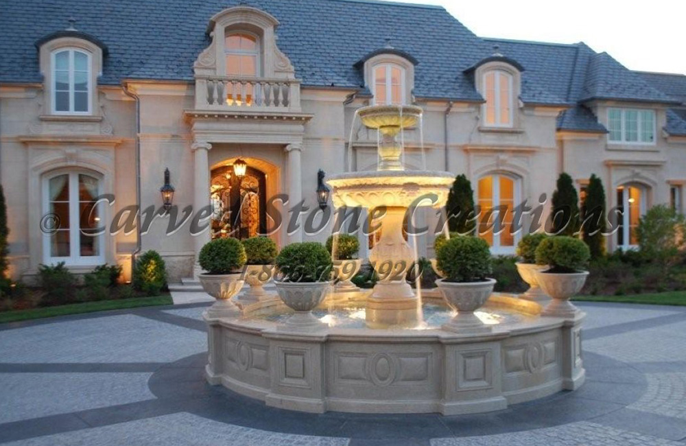 2-Tier Run Fountain with Tall Pool Surround and granite Planters carved of Golden Cypress Granite to match the color of the LImestone Estate behind the fountain.