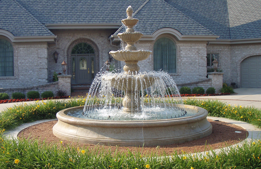 Tall 4-tier Fountain with a 12 Ft diameter x 18 inch tall Flared Contour Pool Surround and a 10 Ft Copper Spray Ring. Both stone items carved of Giallo Fantasia Granite.