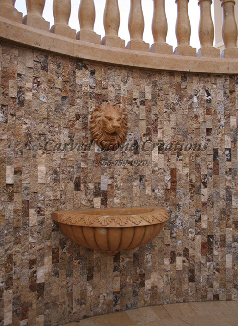 Lion Spitter Fountain and acanthus relief carved basin carved of Henan Yellow Limestone mounted on a scabos travertine rockfaced mosaic wall.